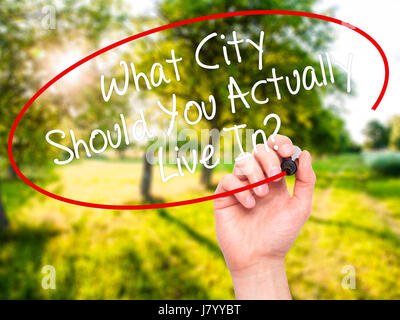 Man Hand writing What City Should You Actually Live In? with black marker on visual screen. Isolated on background. Business, technology, internet con Stock Photo