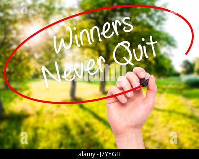 Man Hand writing Winners Never Quit with black marker on visual screen. Isolated on background. Business, technology, internet concept. Stock Photo Stock Photo