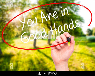 Man Hand writing You Are in Good Hands with black marker on visual screen. Isolated on nature. Business, technology, internet concept. Stock Photo Stock Photo