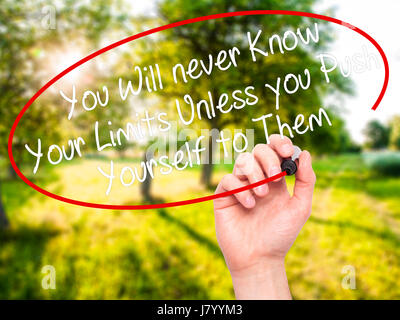 Man Hand writing You Will never Know Your Limits Unless you Push Yourself to Them with black marker on visual screen. Isolated on nature. Business, te Stock Photo