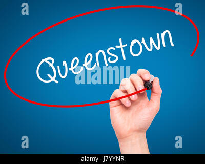 Man Hand writing Queenstown  with black marker on visual screen. Isolated on blue. Business, technology, internet concept. Stock Photo Stock Photo