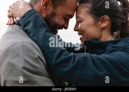 Close-up side portrait of a young couple in love to looking each other lovingly and leaning their heads on each other. Stock Photo