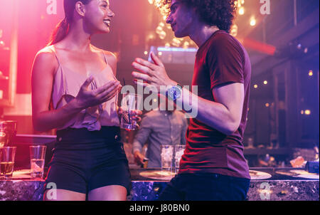 Shot of young man and woman enjoying a party. Couple talking at a nightclub. Stock Photo