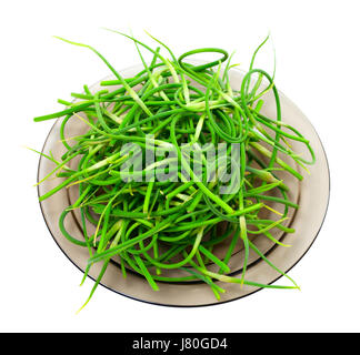 Fresh garlic scapes on plate. Isolated on white background. Stock Photo