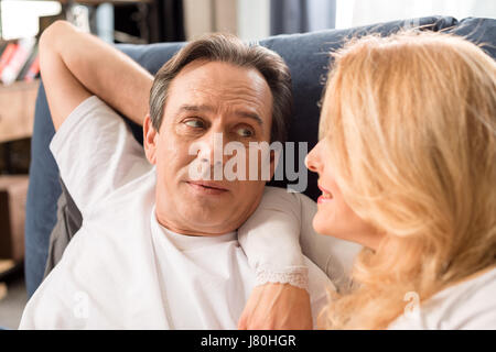 Happy middle aged couple looking at each other and lying on bed at home Stock Photo