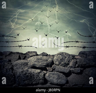 Stone wall fence of a prison with barbed metallic wire on top transform into flying birds over the lightning sky background. Freedom and success conce Stock Photo