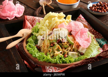 Asinan Betawi, the raw vegetables salad with spicy peanut dressing from Jakarta. Served with yellow noodle and pink crackers. Stock Photo