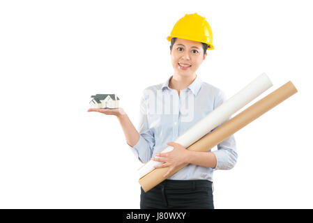 portrait of engineer who hands showing model house and holding many building blueprint isolated on white wall over copyspace. Concept of architect and Stock Photo