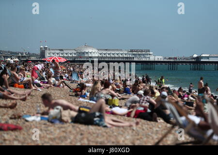 People enjoy the warm weather on Brighton Beach, East Sussex, as Britons hoping for a scorching bank holiday may be disappointed as forecasters predict temperatures will start to drop on Saturday with a chance of rain and thunderstorms throughout the long weekend. Stock Photo