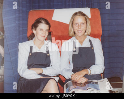 Two Stewardesses Sit on a Airplane Cabin Jump Seat, Pan American World Airways, circa 1970's Stock Photo