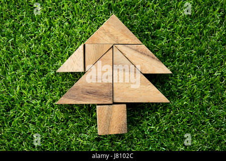 Wood tangram puzzle in Christmas tree shape on artificial green grass background Stock Photo