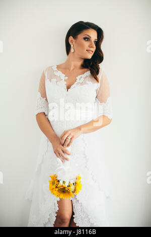 Beautiful young bride posing in a wedding dress and holding a sunflower bouquet Stock Photo