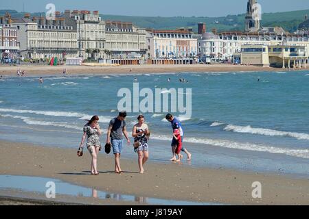 Weymouth, Dorset, UK. 26th May, 2017. Beach goers enjoy a stroll under a clear blue sky at the quieter end of Weymouth's award Winning beach as temperatures continue to climb. Credit: Tom Corban/Alamy Live News Stock Photo
