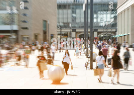 crowd of people on a shopping street in out of focus view Stock Photo