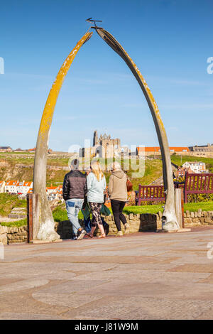 Three people waking through the Whalebone Arch, Whitby, North Yorkshire, England, UK. The bones are from a bowhead whale, and were acquired by Whitby  Stock Photo
