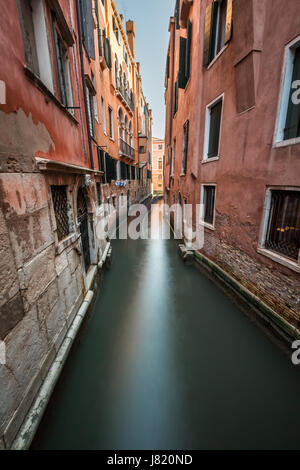 Narrow canal among old colorful brick houses in Venice, Italy Stock ...