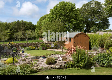 A Dutch style wooden garden shed with patio and two chairs 