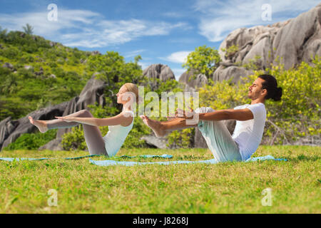 couple making yoga half-boat pose outdoors Stock Photo