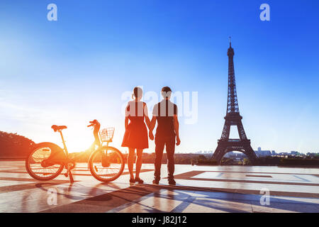 Couple with bicycle looking at Eiffel Tower and holding hands on Trocadero in the morning in Paris, city of love Stock Photo