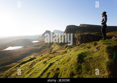 Woman standing on Quiraing plateau and looking at sunrise, Isle of Skye, Scotland, UK. Stock Photo