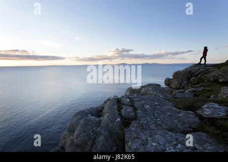 Woman standing on the cliffs near Neist Point at twilight, Isle of Skye, scotland, UK. Stock Photo