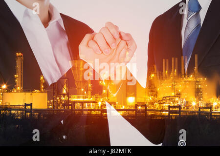 double exposure of arm wrestling between businessman and businesswoman with industrial oil refinery plant background Stock Photo