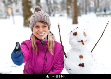 Picture of a beautiful girl posing next to a snowman Stock Photo