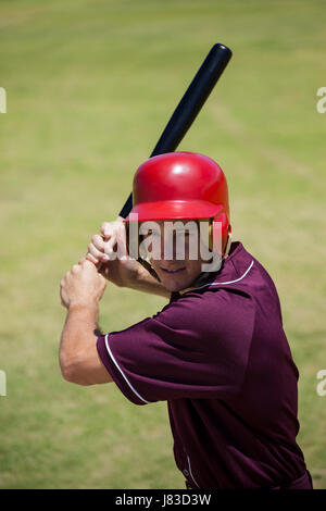 Confident baseball player with bat hitting at field during match Stock Photo