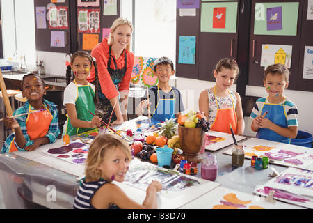 Portrait of smiling teacher and schoolkids in drawing class Stock Photo
