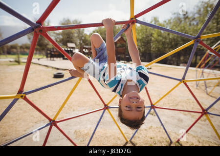 Portrait of happy schoolboy playing on dome climber at school playground Stock Photo