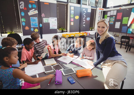 Teacher helping schoolgirl with her homework in classroom at school Stock Photo