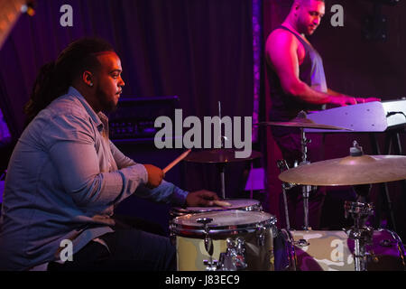 Drummer playing on drum set on stage in nightclub Stock Photo