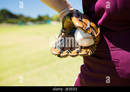 Mid section of baseball pitcher holding ball in glove on sunny day Stock Photo