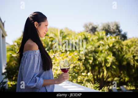Side view of pretty woman holding red wine glass in restaurant Stock Photo