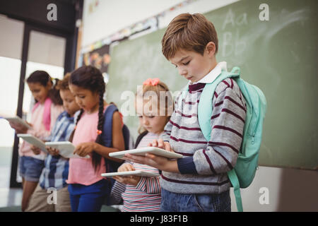 Attentive schoolkids using digital tablet in classroom at school Stock Photo