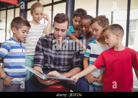 Teacher teaching schoolkids in library at school Stock Photo