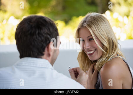 Rear view of man proposing his girlfriend at restaurant Stock Photo