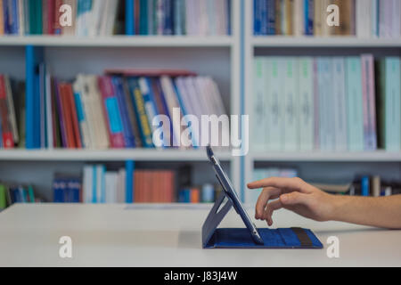 Guy or man or student or businessman touch a tablet with a blank screen on a white desk in library Stock Photo