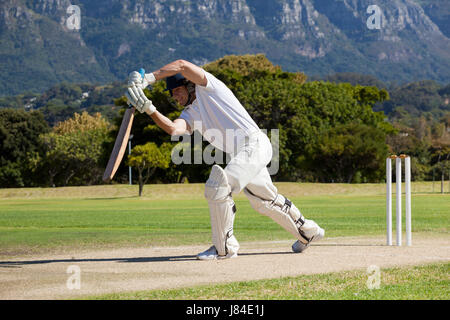 Full length of cricketer playing on field during sunny day Stock Photo