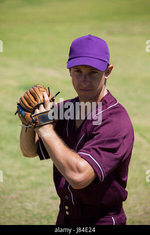 Portrait of confident baseball player wearing gloves standing at field Stock Photo
