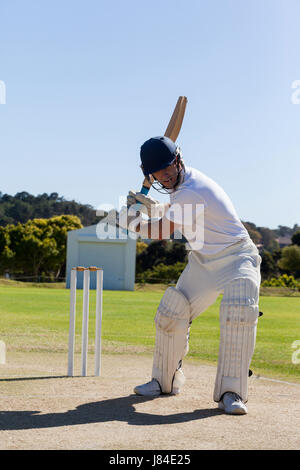 Full length of determined cricketer playing on field during sunny day Stock Photo