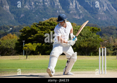 Full length of cricket player playing on field during sunny day Stock Photo