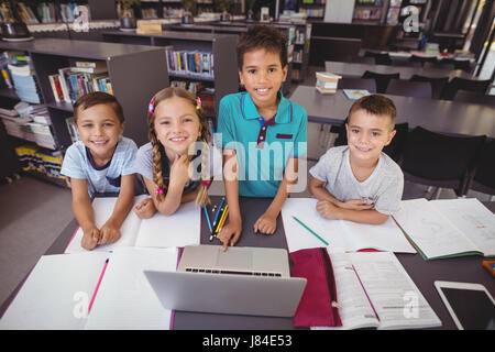Portrait of schoolkids using laptop in library at school Stock Photo