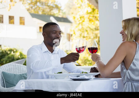 Young couple toasting red wine while sitting at restaurant Stock Photo