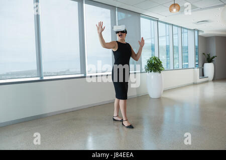 Young female executive using virtual reality headset in office Stock Photo