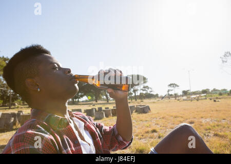 Young man having a beer in the park on a sunny day Stock Photo