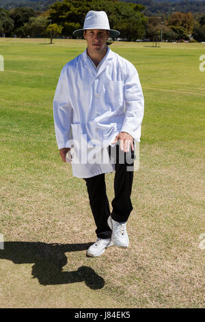 Portrait of cricket umpire signaling leg bye on sunny day during match Stock Photo