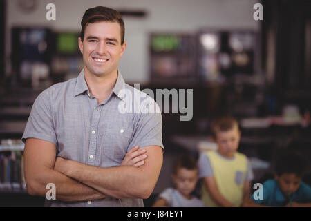 Portrait of happy teacher holding with arms crossed in library at school Stock Photo
