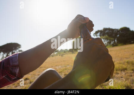 Man opening the lid of beer bottle on a sunny day Stock Photo