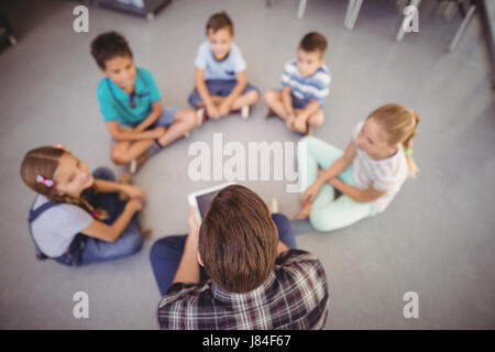 Overhead view of teacher and schoolkids sitting in library at school Stock Photo
